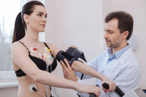 Medico competente moderno che utilizza strumenti speciali per misurare la pressione sanguigna — Foto Stock
