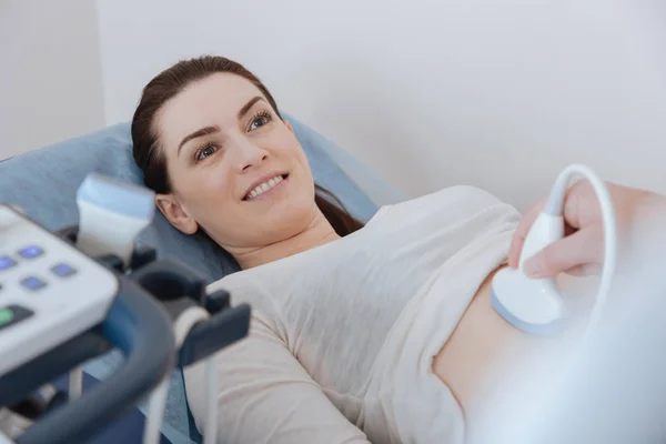 Удовлетворенная очаровательная женщина лежит на медицинской кровати во время процедуры — стоковое фото