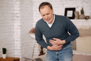 Old man feeling big discomfort in stomach.
