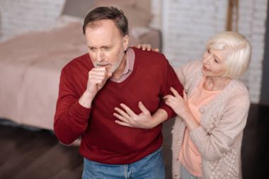 Aged man coughing near his wife clipart