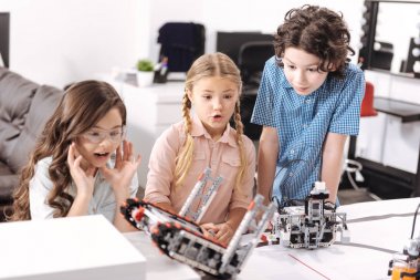 Şaşırmış gibi öğrenciler okulda elektronik robotlar test