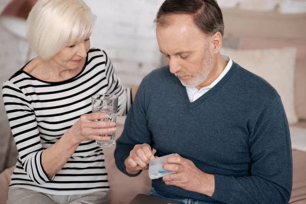 Старик собирается принимать таблетки рядом со своей женой — стоковое фото