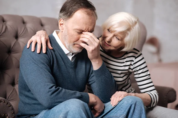 Пожилая женщина успокаивает своего депрессивного мужа — стоковое фото