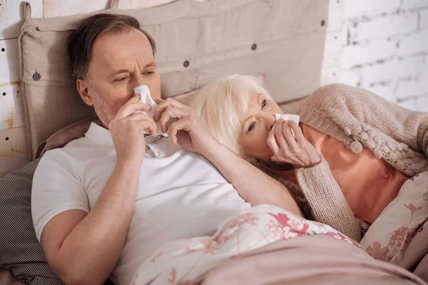 Pereche de vârstnici întinși în pat cu snuffles — Fotografie, imagine de stoc