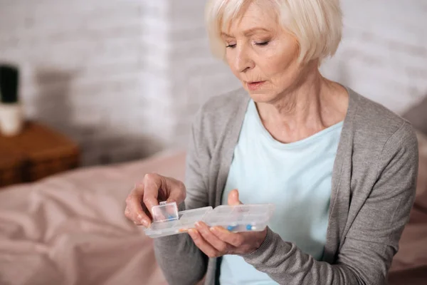 Primer plano de la mujer anciana sosteniendo píldoras caso — Foto de Stock