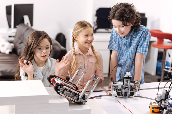 Amazed pupils testing electronic robots at school