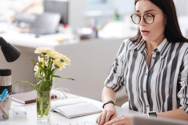 Mujer asustada mirando florero con flores — Foto de Stock