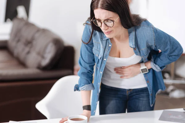 Kind brunette putting left hand on her belly — Stock Photo, Image