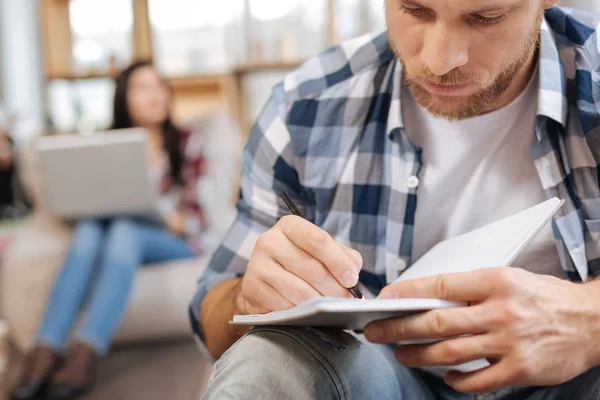 Ernster, konzentrierter Mann, der in das Notizbuch schreibt — Stockfoto