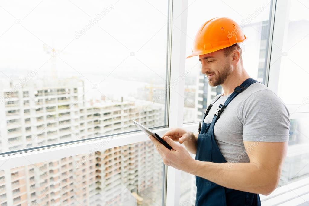 Cheerful construction engineer using tablet