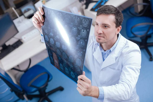 Gutaussehender professioneller Onkologe beim Betrachten der Röntgenbilder des Gehirns — Stockfoto