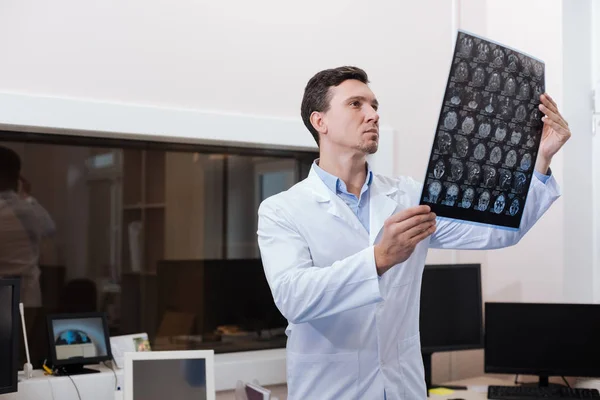 Handsome experienced radiologist looking at CT scan pictures — Stock Photo, Image