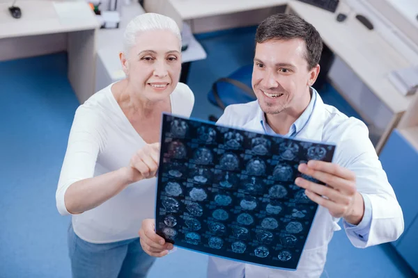 Щаслива старша жінка вказує на фото рентгенівського променя — стокове фото