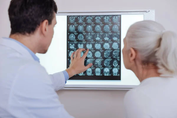 Médico macho agradável mostrando a seu paciente uma foto de raios X — Fotografia de Stock