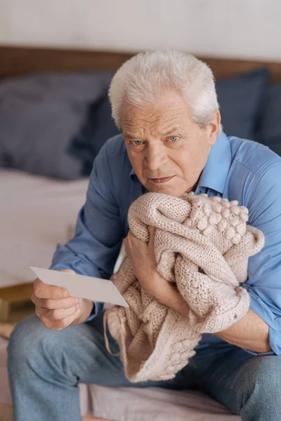 Triste hombre deprimido presionando su chaqueta esposas a su corazón — Foto de Stock