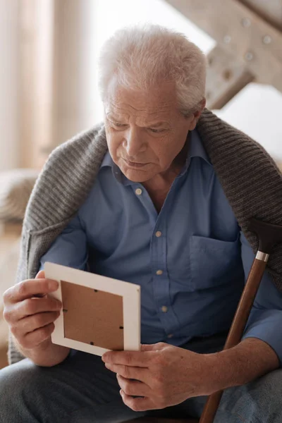 Triste anciano sosteniendo una foto — Foto de Stock