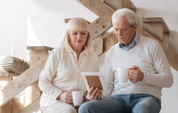 Triest bejaarde echtpaar kijken van de foto — Stockfoto