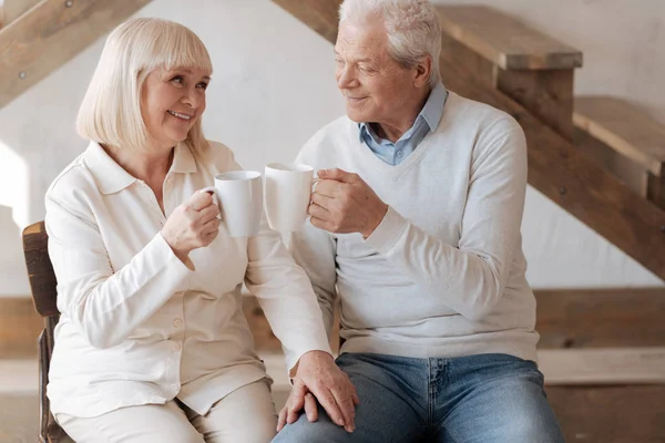 Positive delighted couple clinking cups — Stock Photo, Image