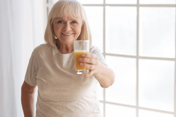 Feliz anciana que le ofrece un vaso de jugo —  Fotos de Stock