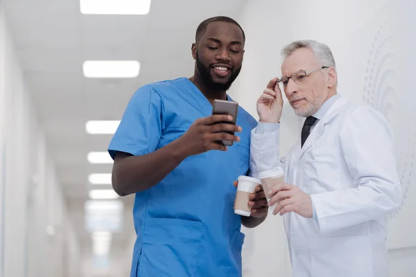 Un stagiaire afro-américain sociable partage des nouvelles avec un collègue senior — Photo