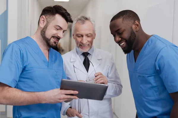 Amüsierte betagte Praktizierende genießt Freizeit mit Kollegen bei der Arbeit — Stockfoto