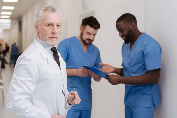 Entschlossener gealterter Kinderarzt kontrolliert Arbeitsprozess in der Klinik — Stockfoto