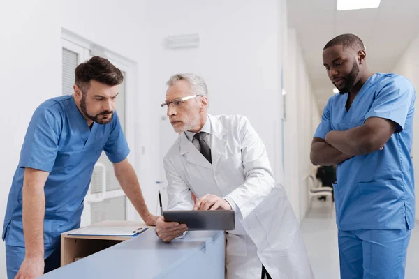 Intelligent åldern utövaren att hjälpa unga kollegor på kliniken — Stockfoto