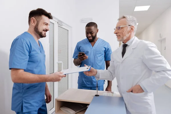 Délicieux médecin vieillissant vérifiant la qualité du travail à la clinique — Photo