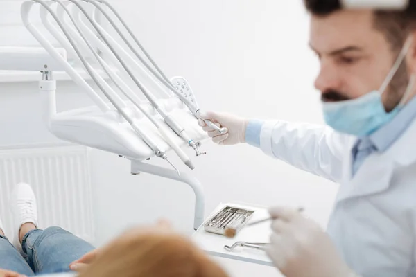 Seriösa noggrann tandläkare arbetar med verktyg — Stockfoto