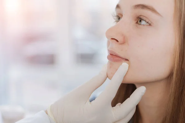 Dermatologista proficiente examinando o rosto do paciente na clínica — Fotografia de Stock