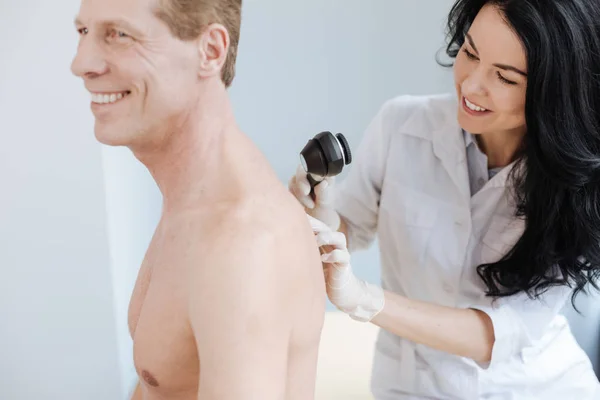 Giovane dermatologo carismatico che utilizza dermatoscopio per il lavoro in clinica — Foto Stock