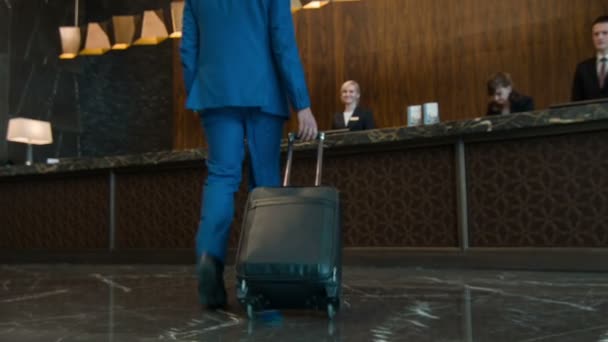 Businessman with suitcase walking to reception desk — Stock Video