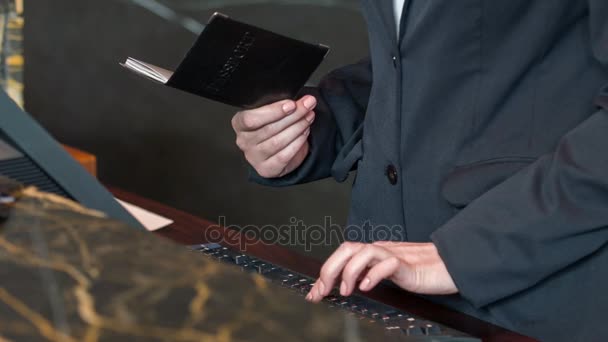 Receptionist holding passport while registrating guest — Stock Video