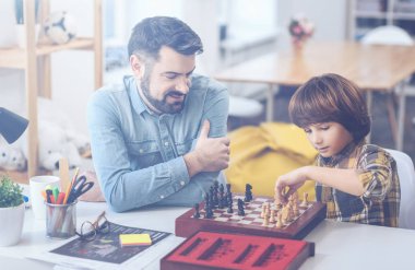 Cute boy playing chess with his father clipart