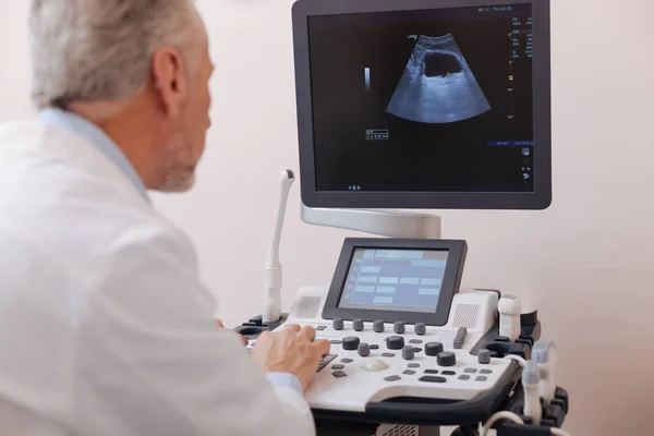 Концентрированный врач, использующий оборудование для сонографии в больнице — стоковое фото