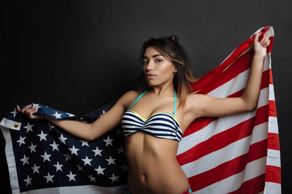 Cheeky Hispanic American woman holding American flag indoors — Stock Photo, Image