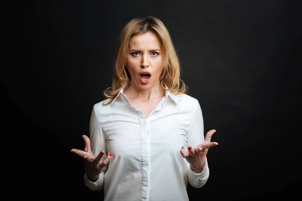 Furious mature woman yelling in the black colored studio — Stock Photo, Image