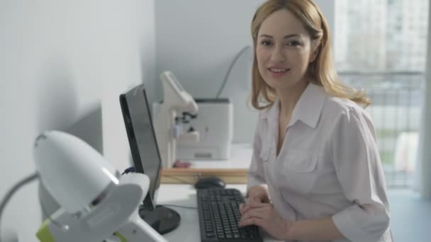 Веселый медицинский работник сидит за компьютером — стоковое видео