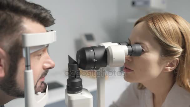 Optometrista feminina fazendo teste de visão para o paciente — Vídeo de Stock