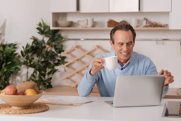 Hombre envejecido alegre usando el ordenador portátil en casa — Foto de Stock
