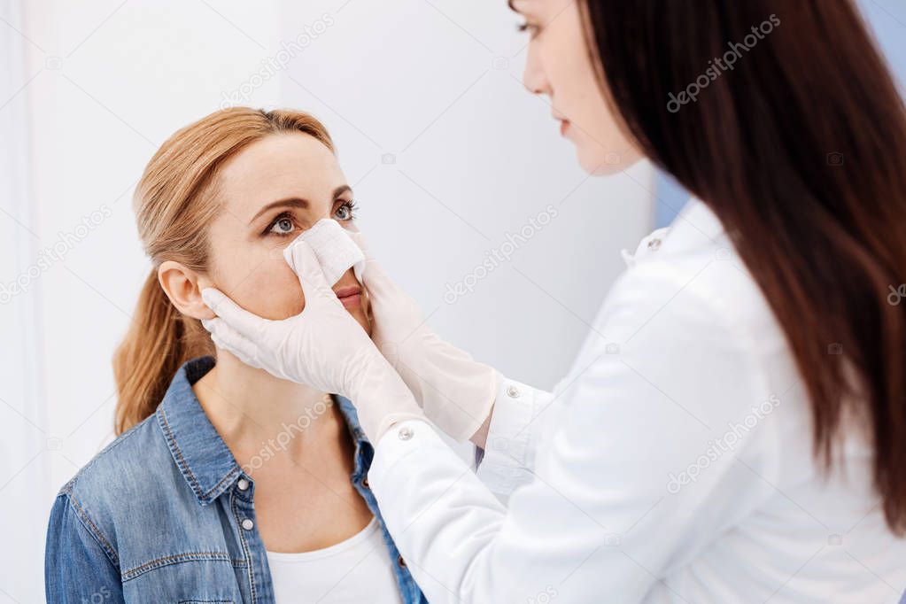 Nice female doctor putting a medical dressing on her patient