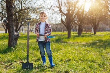 Happy little kid posing for picture in garden clipart
