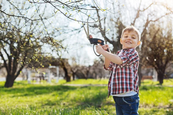 Adorable niño sosteniendo tijeras de podar y sonriendo — Foto de Stock