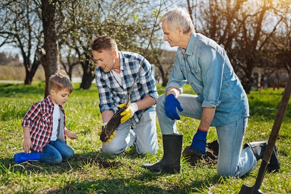 Membros mais velhos da família ensinando criança como se preocupar com a natureza — Fotografia de Stock