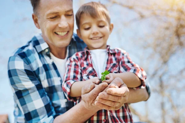 Padre e hijo mirando una pequeña planta en sus manos — Foto de Stock