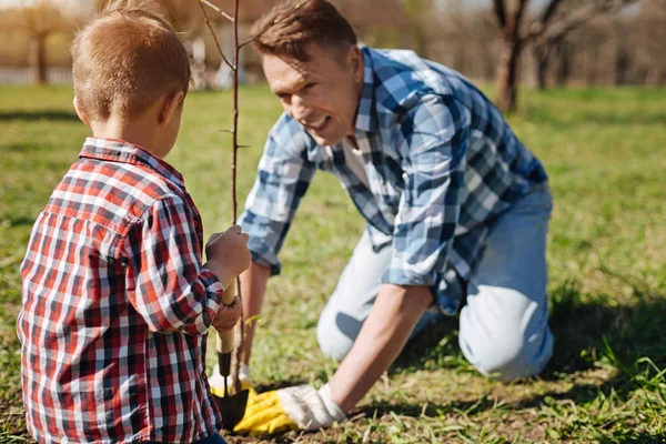Vader en zoon scooping bodem in tuin — Stockfoto
