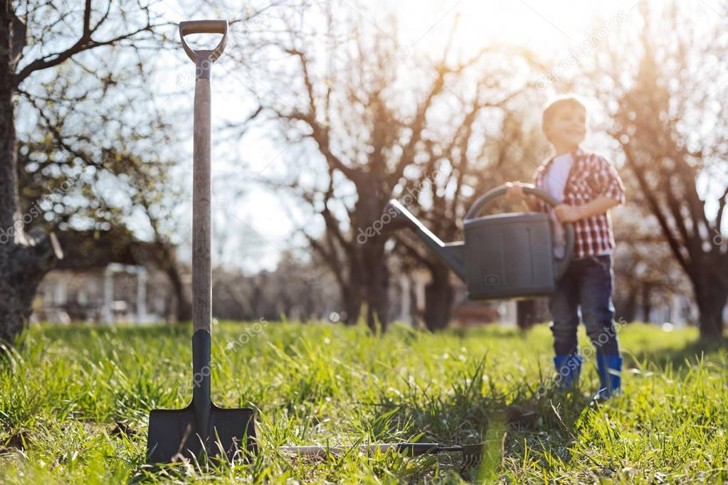 Charming kid holding watering can in garden