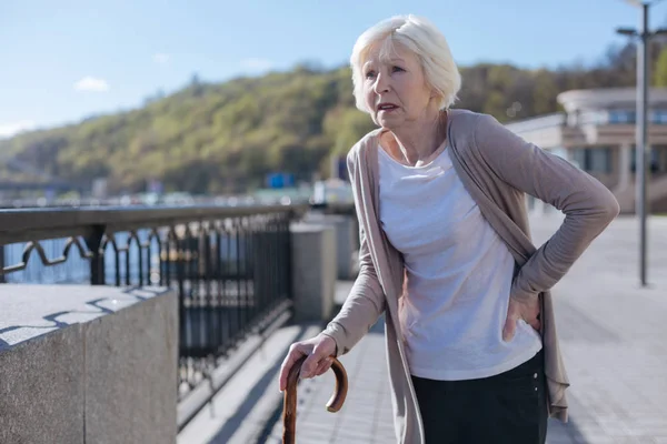 Mulher aposentada com dor lombar durante o passeio — Fotografia de Stock