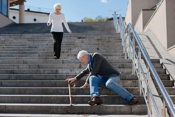 Disappointed pensioner sitting on stairs in the street