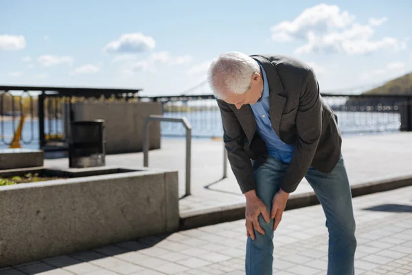 Hombre envejecido con dolor en la rodilla en el paseo marítimo — Foto de Stock